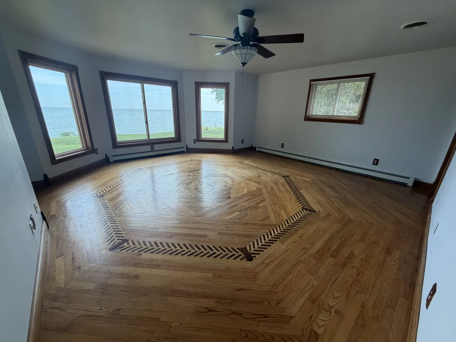 Emptied room with inlaid hardwood floor and lake views after a full estate cleanout