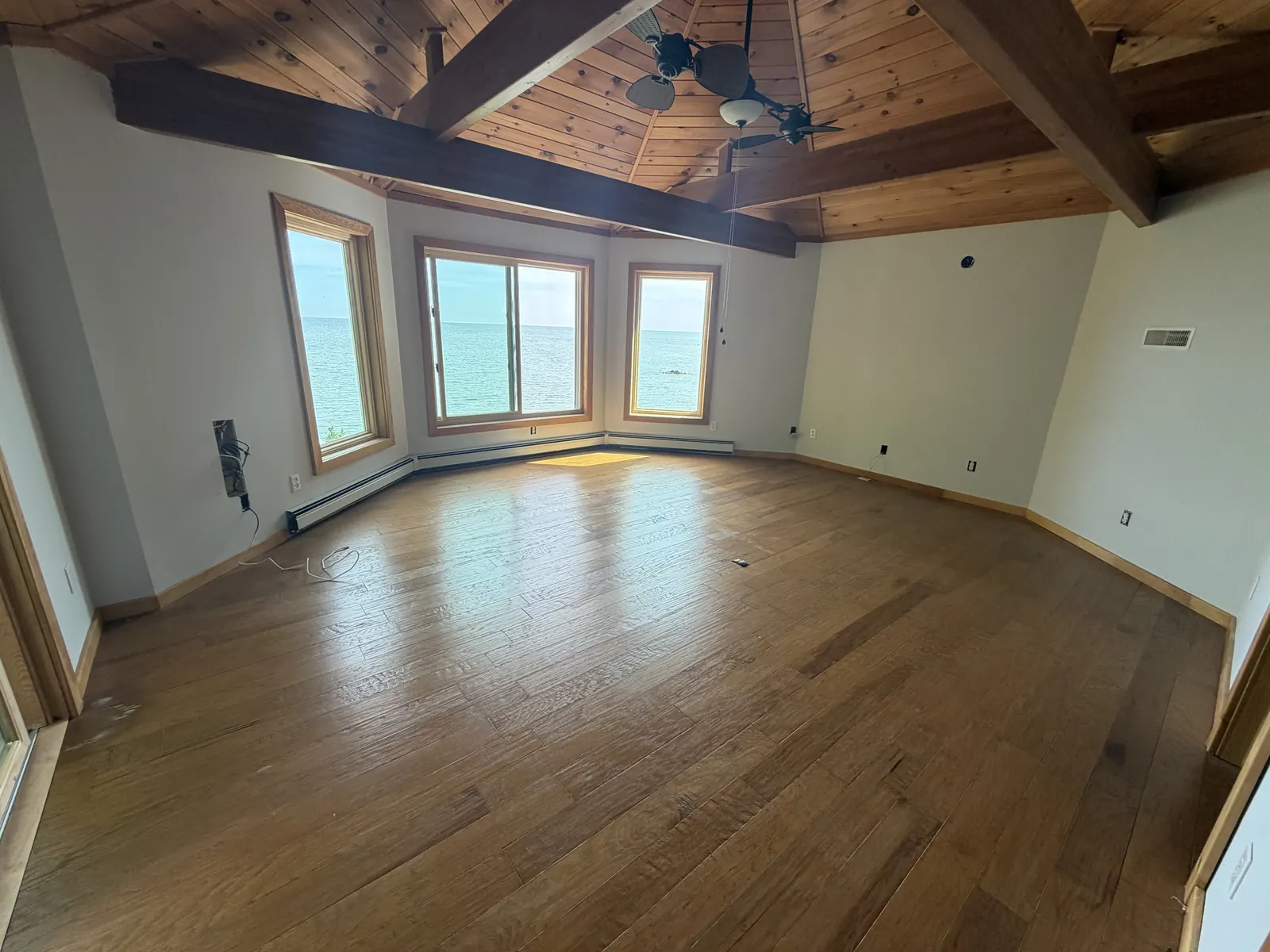 Emptied room with vaulted wood ceiling and lake views after an estate cleanout