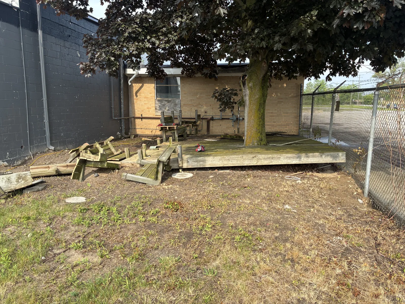 Collapsed deck and lumber debris behind a property before removal